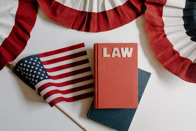 Law book and a small American flag laid out beneath red, white, and blue bunting