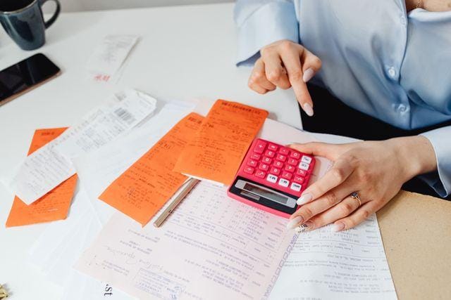 Person working a calculator over a spread of receipts and paperwork