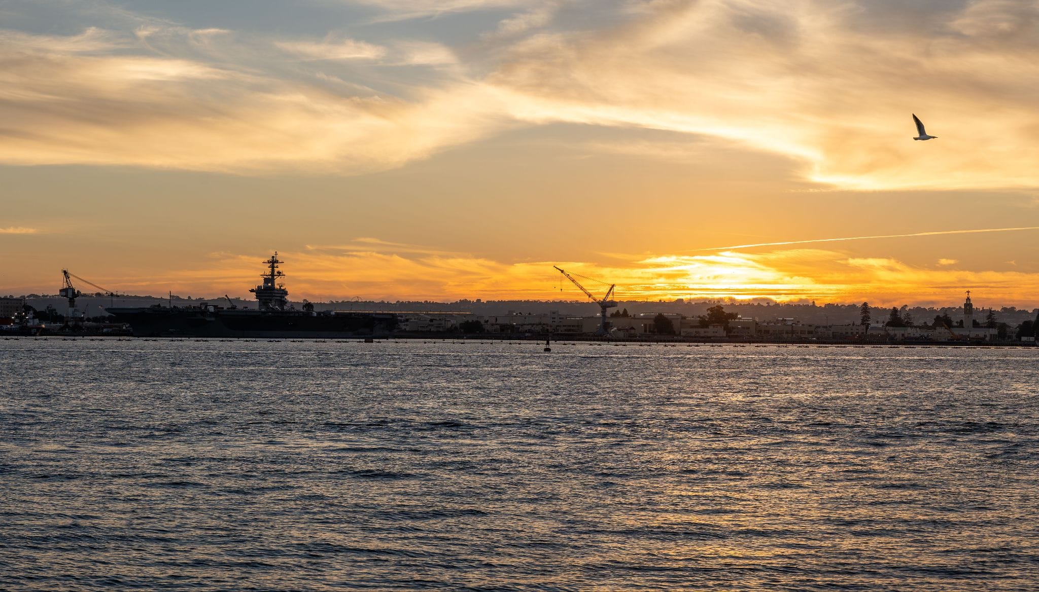 Aircraft carrier moored at a naval base at sunset