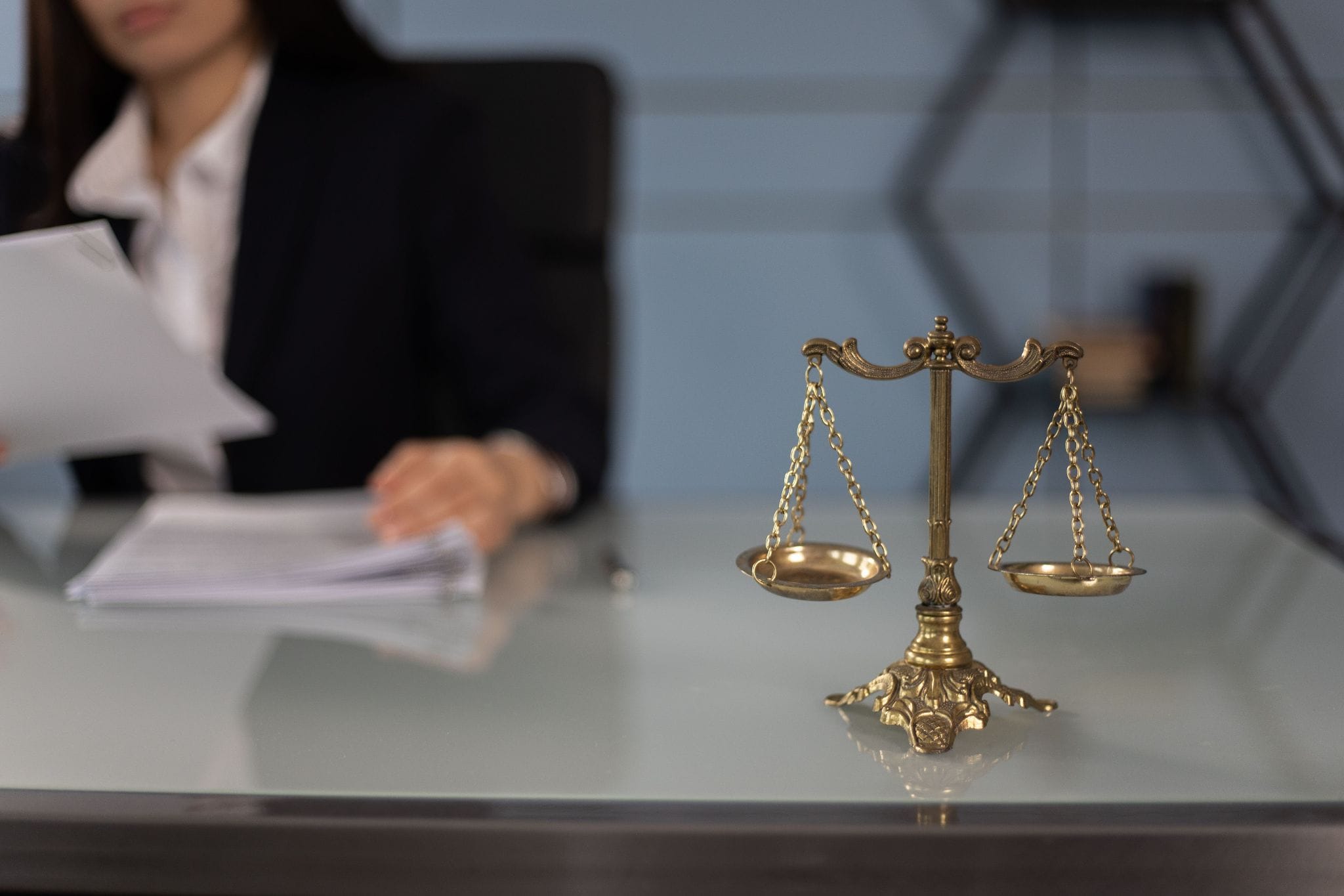 Scales of justice on a desk beside someone reviewing documents