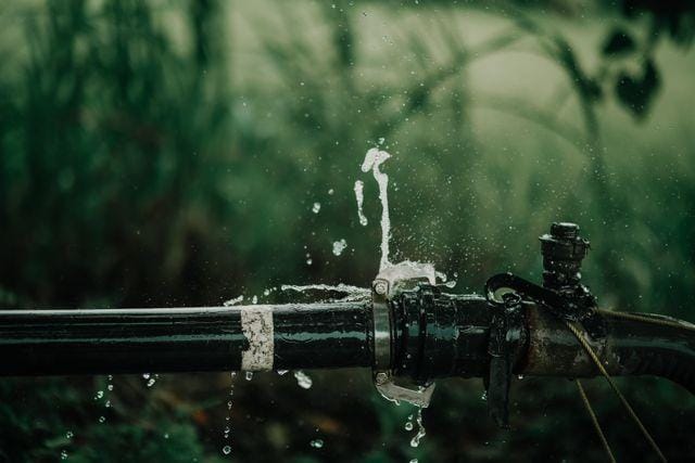 Water spraying from a burst joint on an outdoor pipe