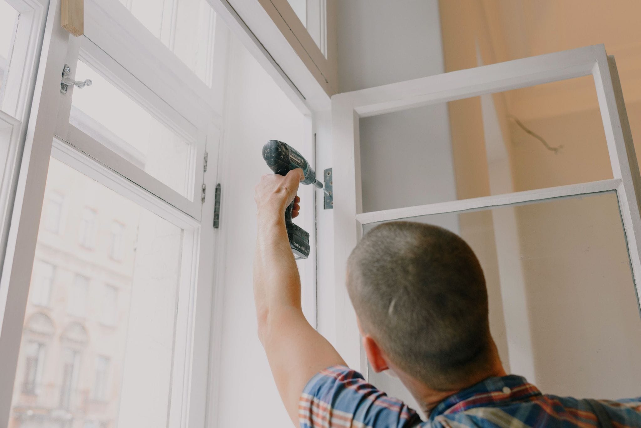 Contractor repairing a window shutter on a residential property